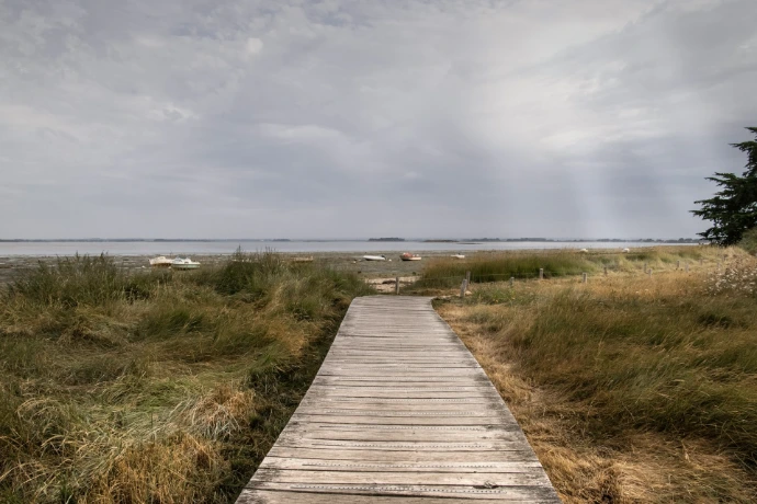a wooden walkway leading to a beach on a cloudy day